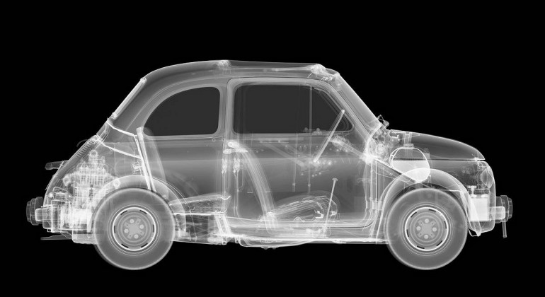 A black-and-white x-ray style image of a classic car, showing its internal mechanical components like engine, seats, and…