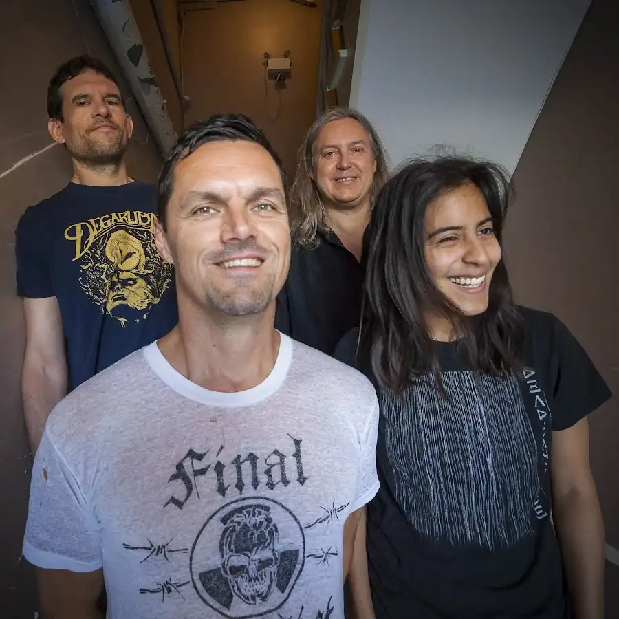 Four people pose together in a hallway, with the person in the foreground wearing a t-shirt that says 'Final' over a skull…