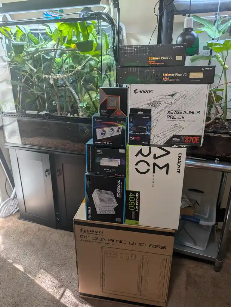 A tall stack of computer hardware boxes, including a Gigabyte RTX 4080 Super, Aorus motherboard, AMD Ryzen 9 CPU, and Lian…