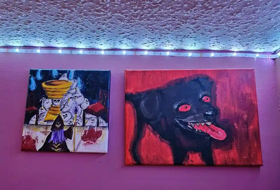 Two paintings hang on a purple wall under blue LED strip lights; the left depicts a dark fantasy scene with a figure and…