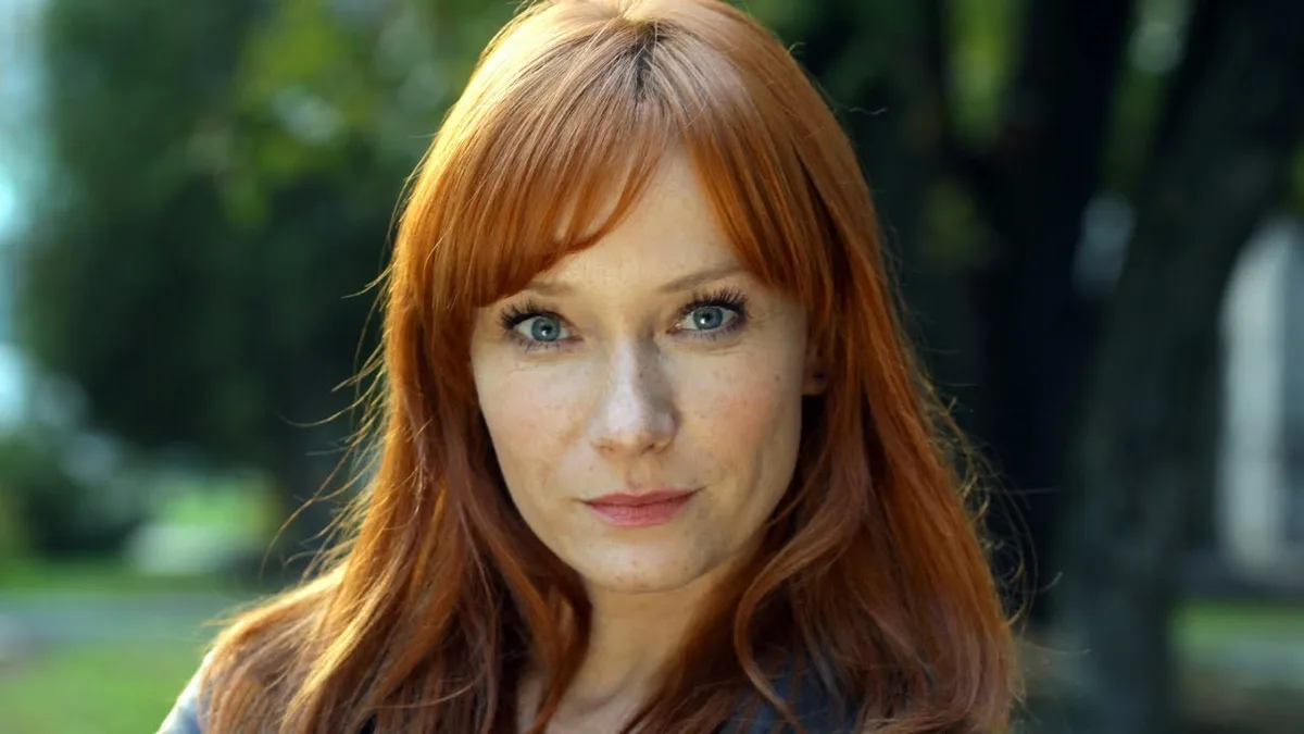 A woman with red hair and freckles stares directly at the camera with a neutral expression. The overlaid text reads 'i'm not…