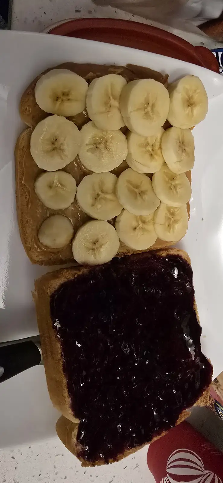 A sandwich made with two slices of bread, one topped with peanut butter and numerous banana slices arranged neatly, the…