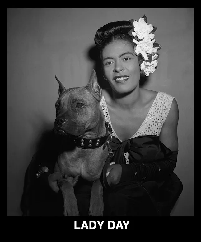 A black-and-white portrait of a woman with an elegant updo adorned with white flowers, wearing a dark dress with a white…