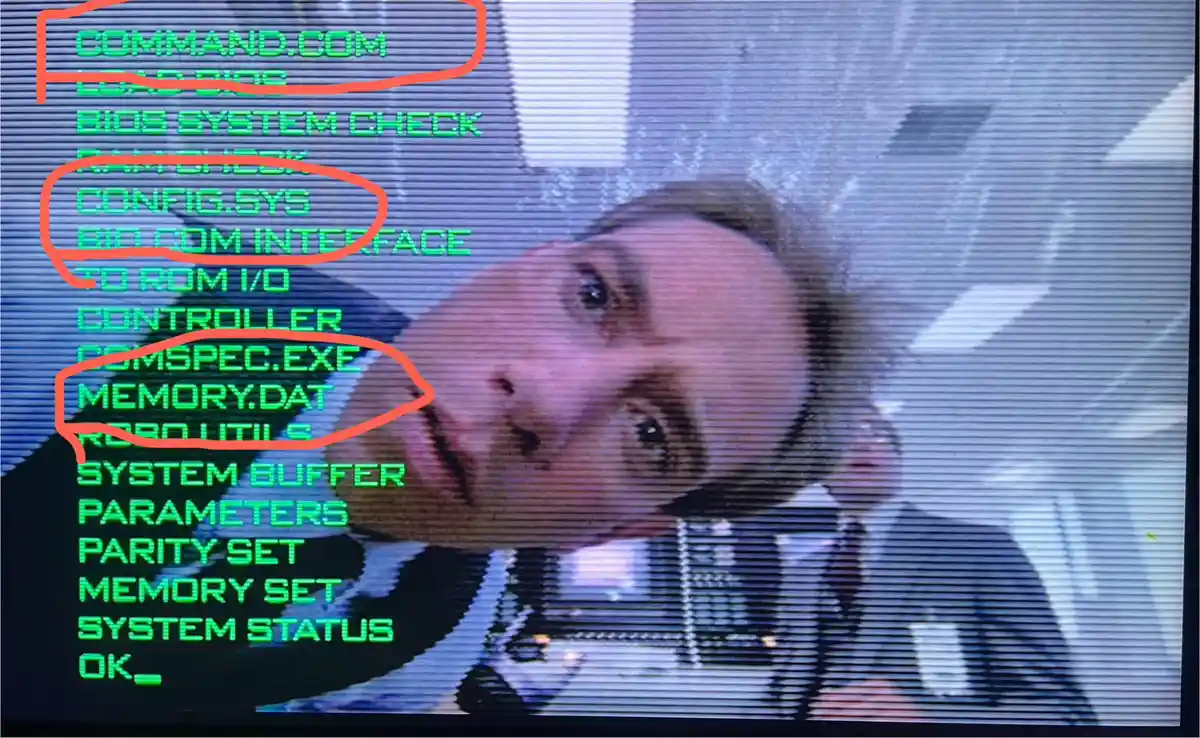 A screenshot of a computer screen displaying green text from a DOS-style command prompt, overlaid with a close-up of a man's…