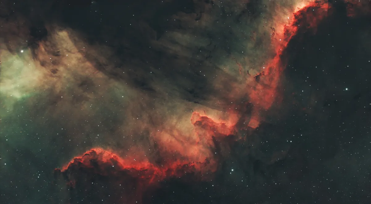 A cosmic nebula image with swirling red, orange, and green clouds against a starry black background, overlaid with the text…