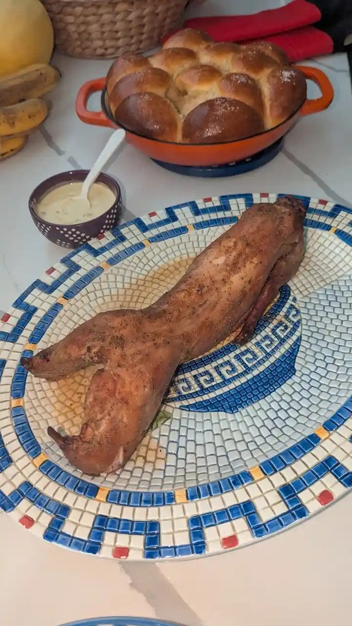 A roasted chicken leg, seasoned and cooked, rests on a decorative blue, white, and red mosaic plate. In the background…