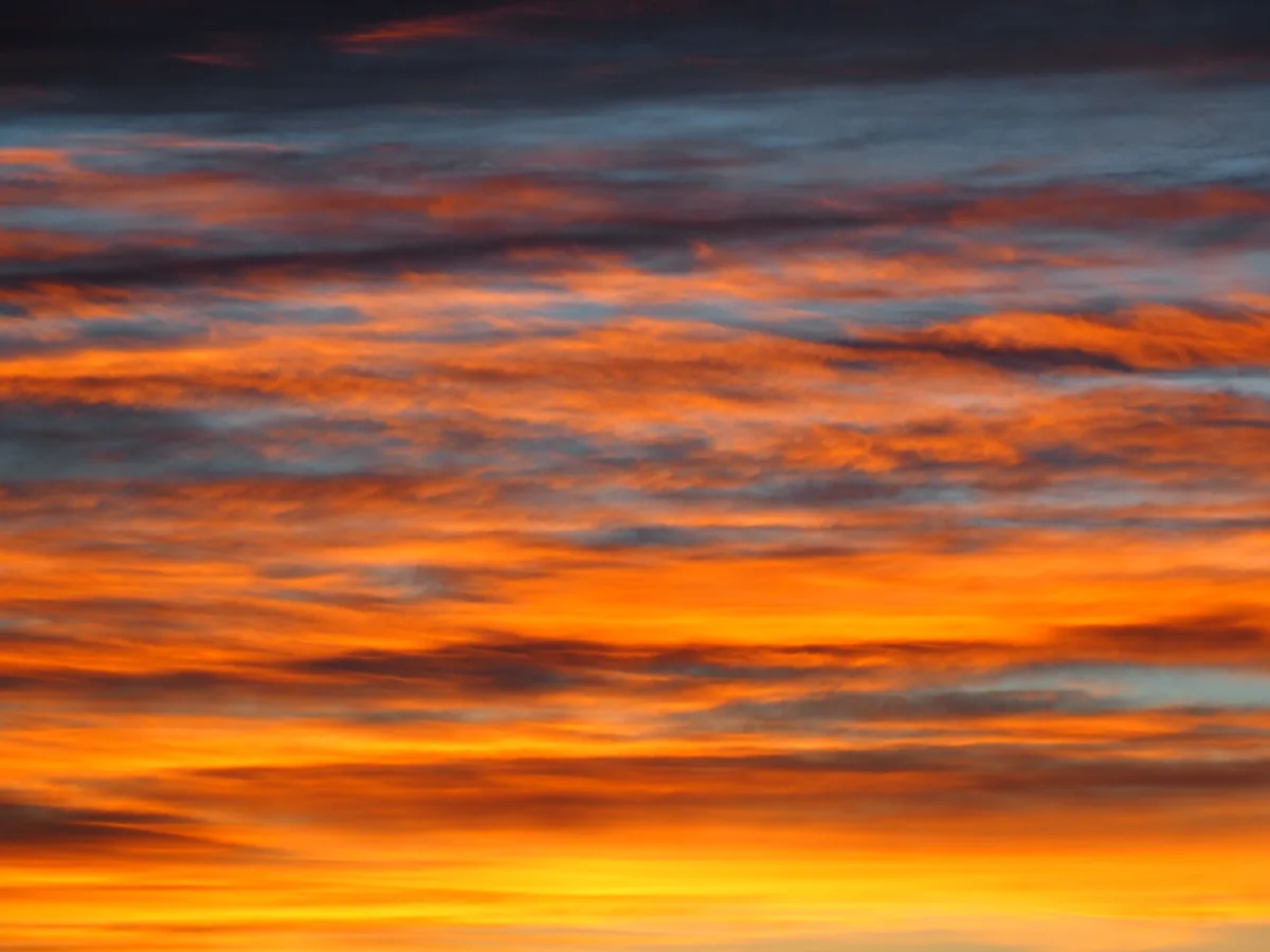 A vibrant sunset sky with streaks of orange, red, and blue clouds. The overlaid text reads 'i'm not crying, you're crying'.
