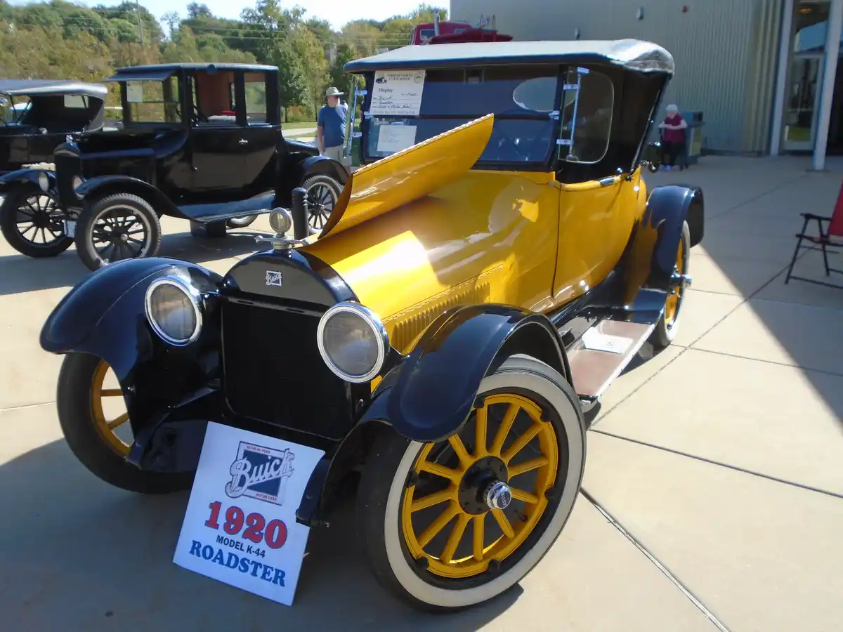 A vintage 1920 Buick Model K-44 Roadster, painted yellow and black with white-walled tires, is displayed outdoors at a car…