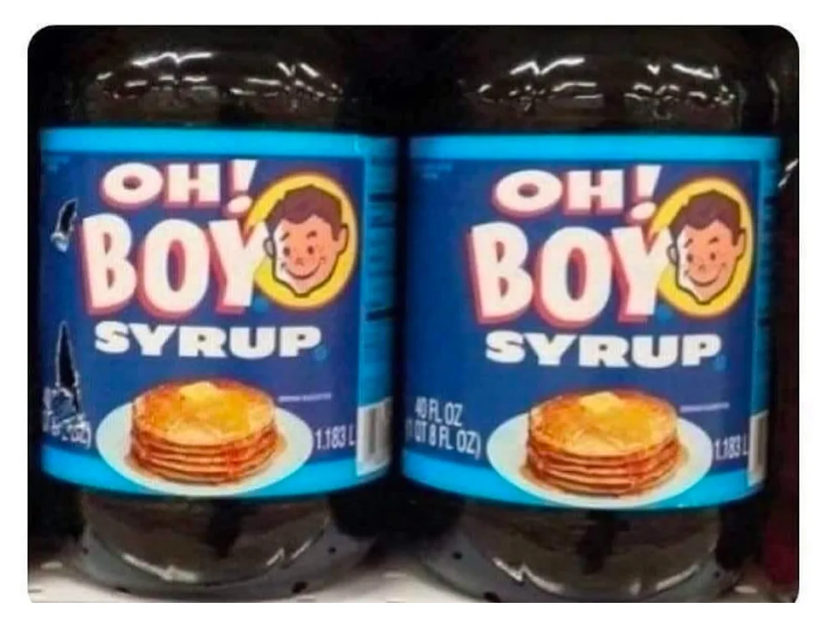Two large plastic bottles of 'OH! BOY SYRUP' are shown side-by-side on a shelf, each with a blue label featuring a cartoon…