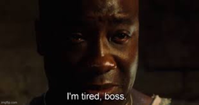A close-up of a Black man with a weary, exhausted expression, his eyes slightly red and glistening, looking directly at the…