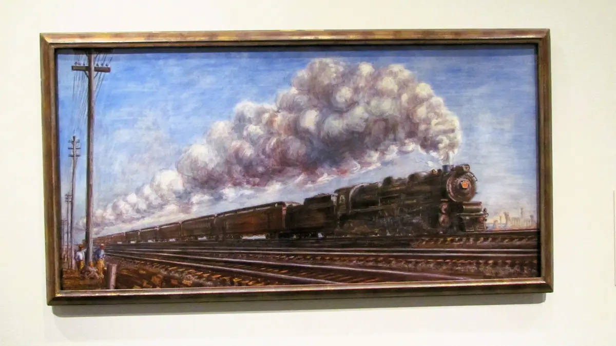A framed painting depicts a steam locomotive pulling freight cars along railway tracks under a cloudy sky, with utility…