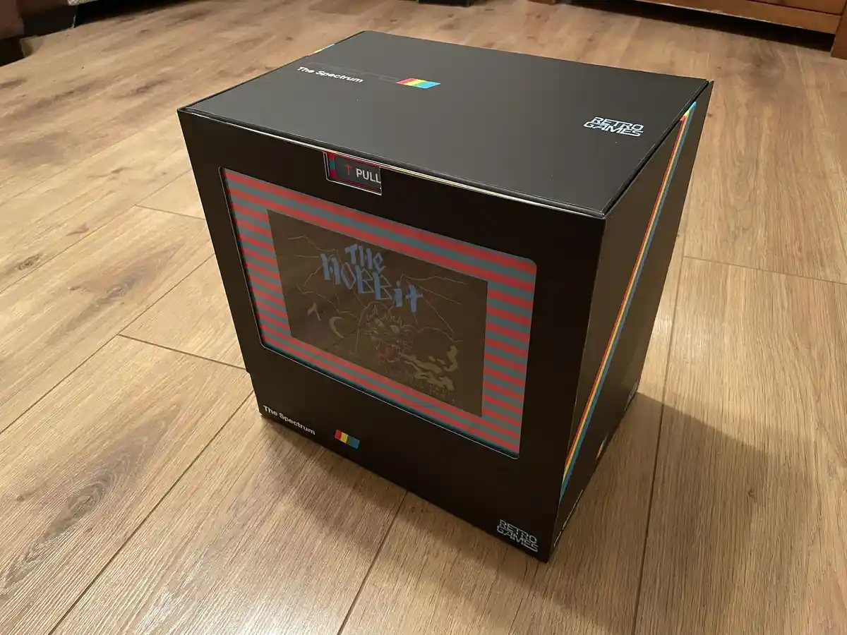A black box designed to look like a retro computer, labeled 'The Spectrum' and 'RETRO GAMES', sits on a wooden floor. It…