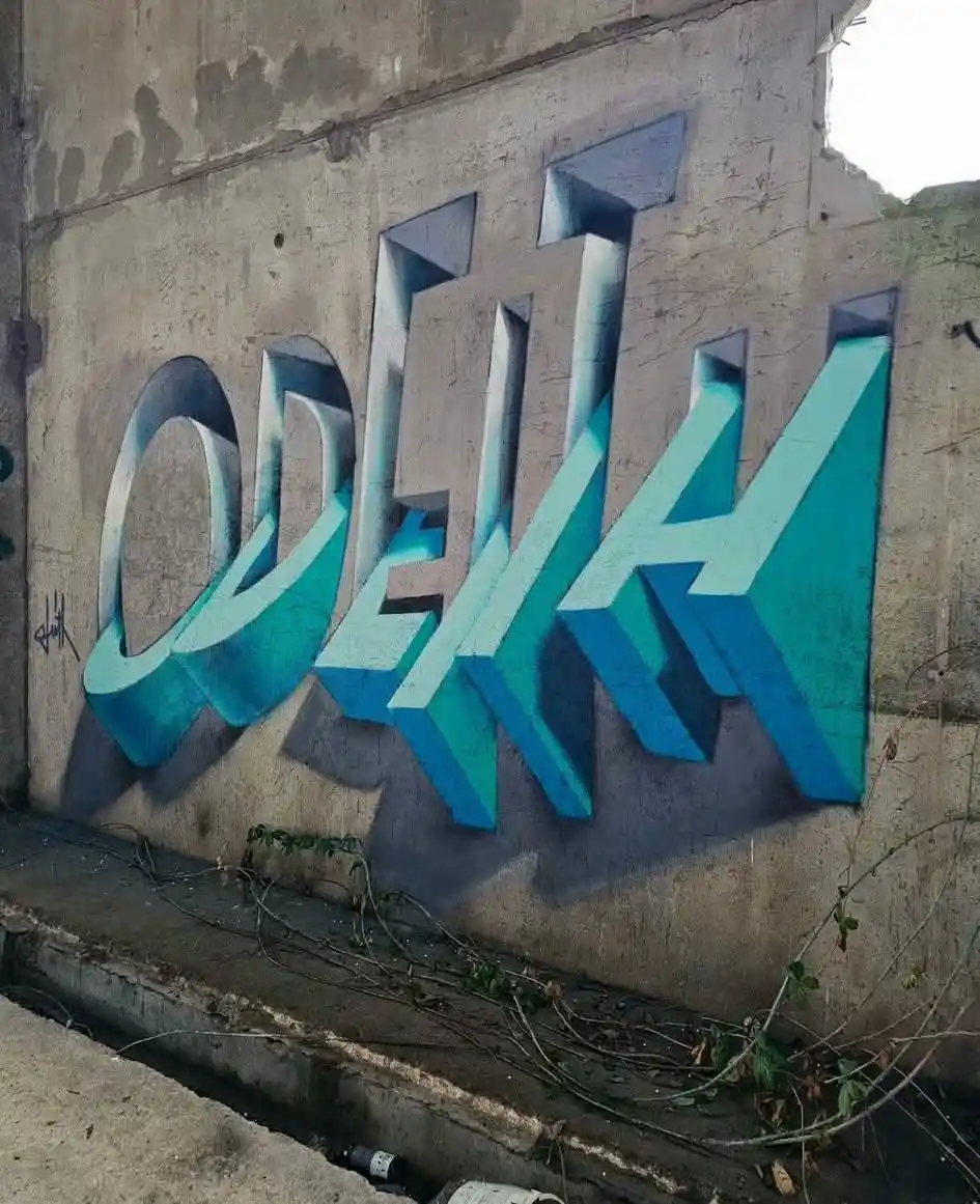 A photograph of a concrete wall with large, stylized 3D graffiti letters spelling 'ODEKH' in shades of blue and teal…