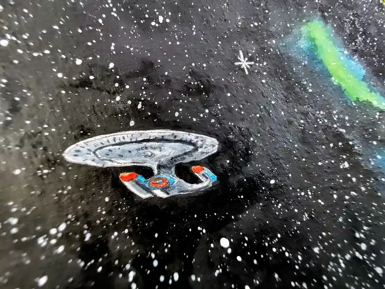 A hand-drawn watercolor painting depicts a Starfleet starship, resembling the USS Enterprise, floating in a starfield with…