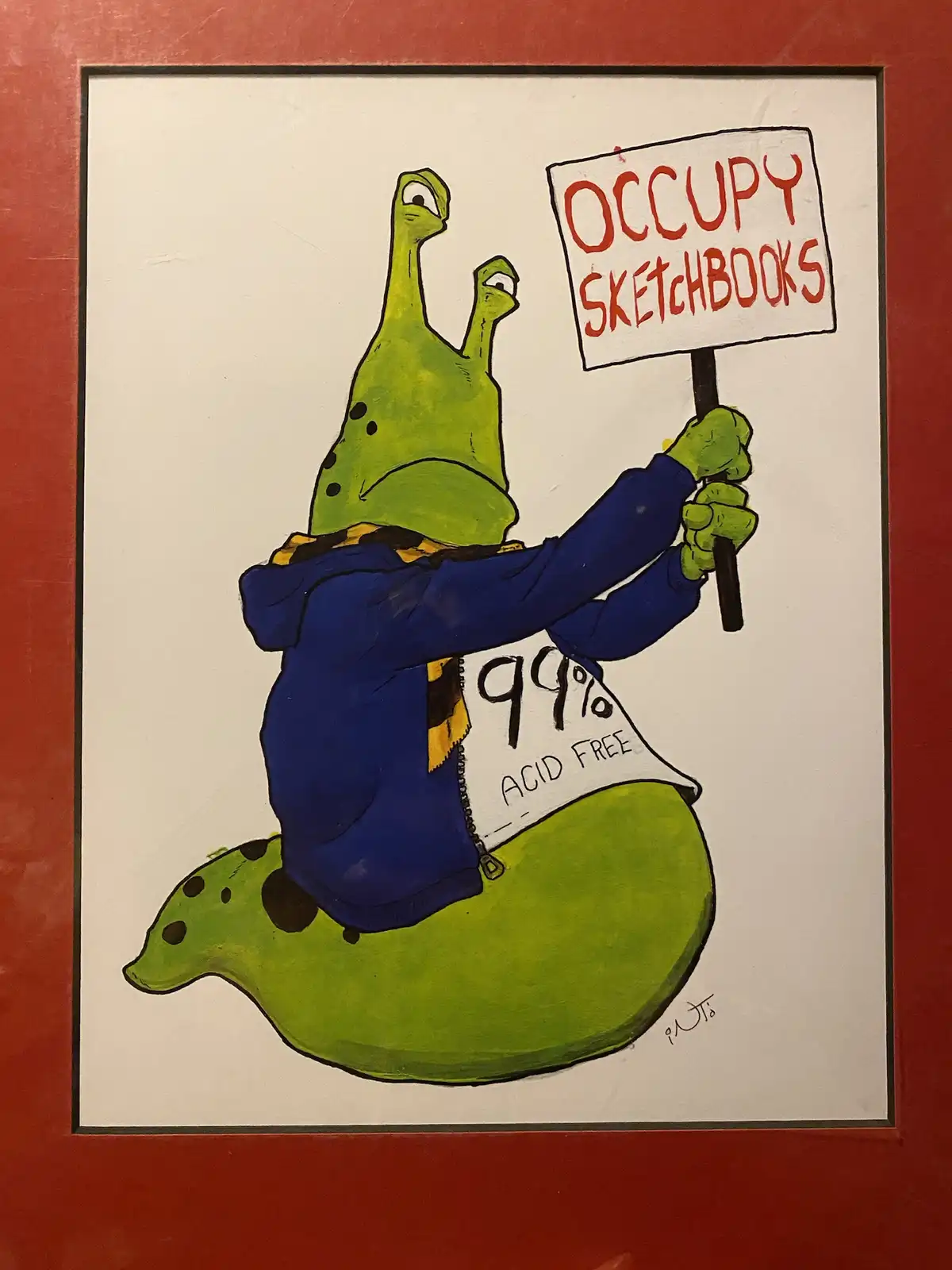 A cartoon green slug wearing a blue hoodie and a yellow scarf holds a protest sign reading 'OCCUPY SKETCHBOOKS' while a…