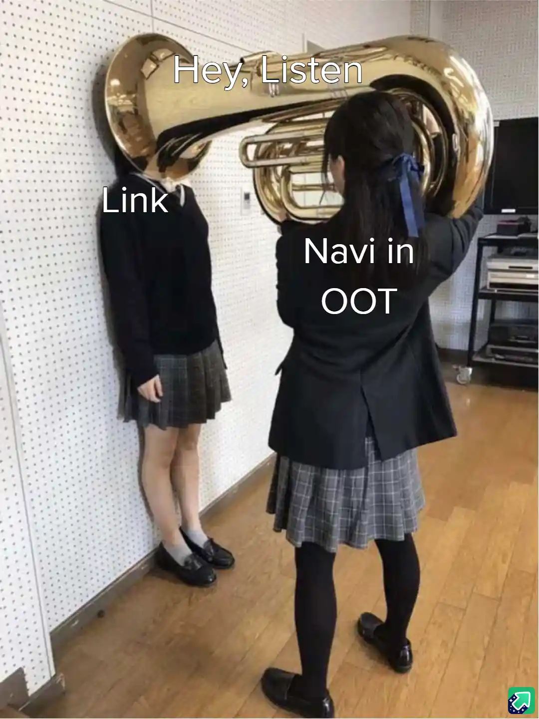 Two girls in school uniforms stand in a room; one holds a large brass tuba, using it to obscure her face, while the other…
