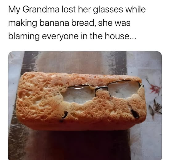 A loaf of golden-brown banana bread with a pair of eyeglasses embedded in its center, as if baked into it. The text above…
