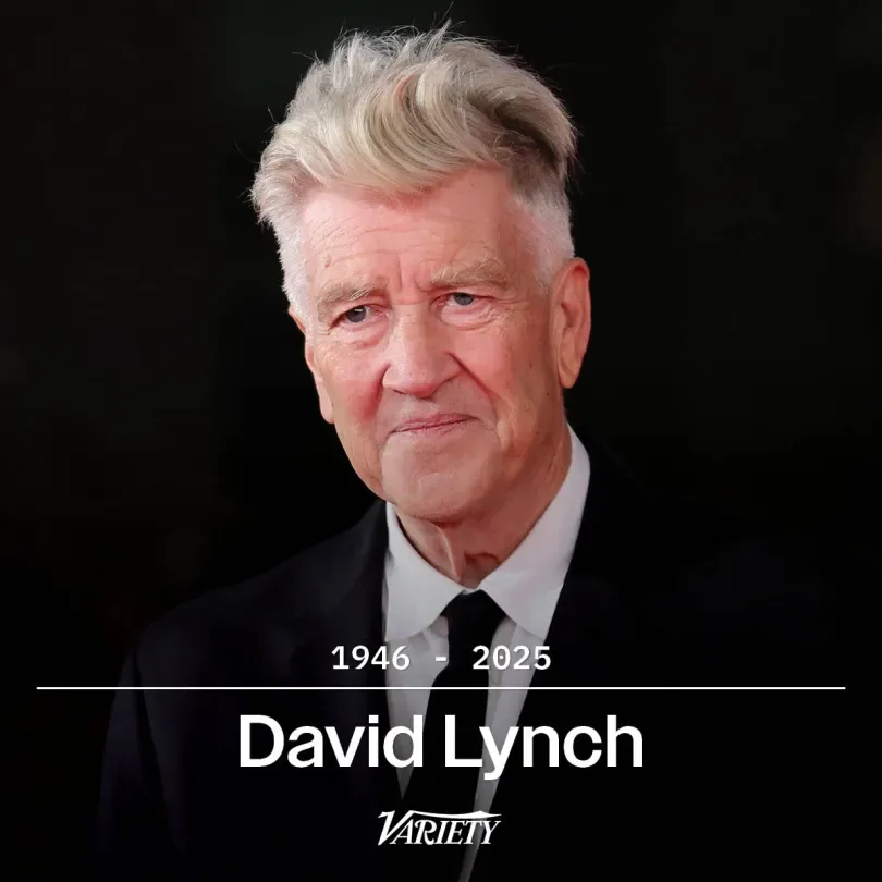 A formal portrait of David Lynch, an older man with gray hair and a serious expression, wearing a black suit and tie against…