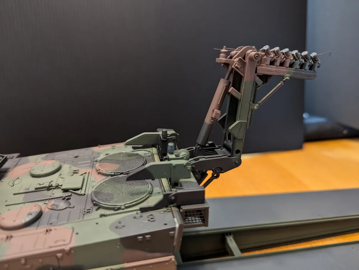A close-up photo of a detailed military vehicle model, likely a tank or armored vehicle, showing its turret and weapon…