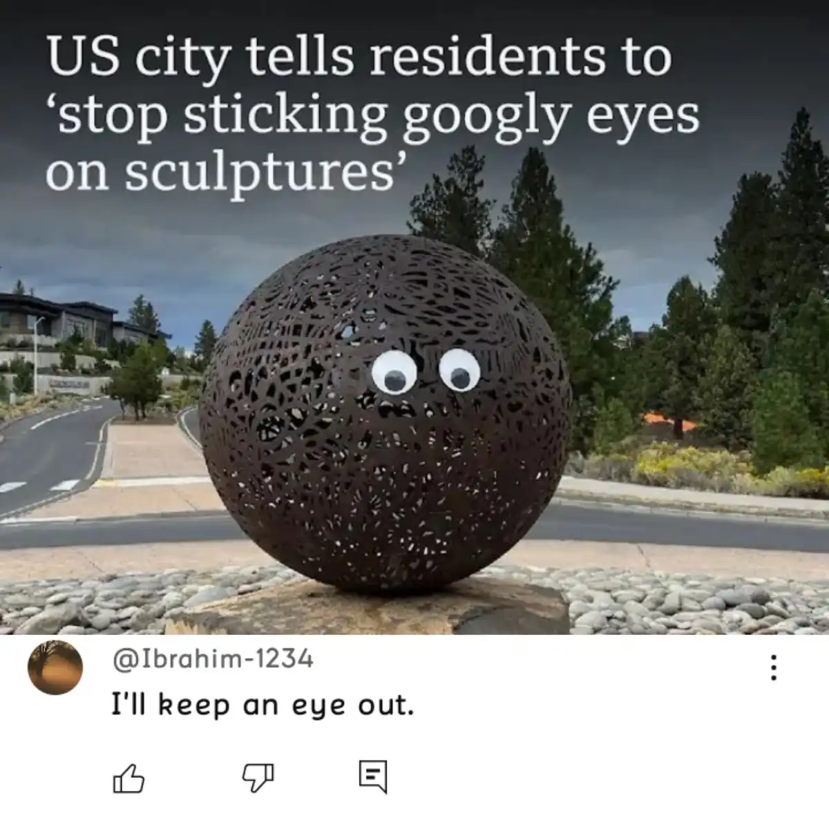 A spherical, dark metal sculpture with a perforated pattern sits outdoors on a stone base, with two large googly eyes stuck…