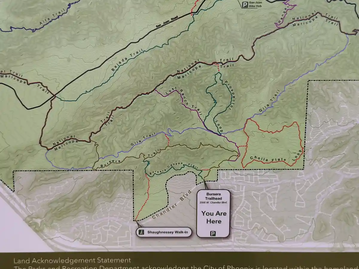 A topographic trail map shows a 'You Are Here' marker at the Bursera Trailhead, with numerous hiking trails radiating…