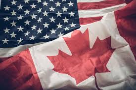 Two national flags, the American flag with stars and stripes and the Canadian flag with a red maple leaf, are draped…
