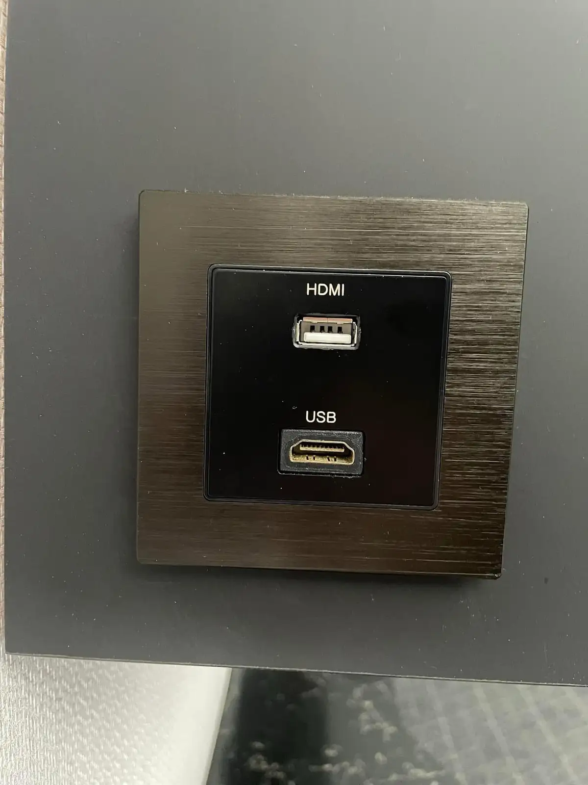 A close-up photo shows a wall plate with two ports: the top port is labeled 'HDMI' and is a USB Type-A connector, while the…
