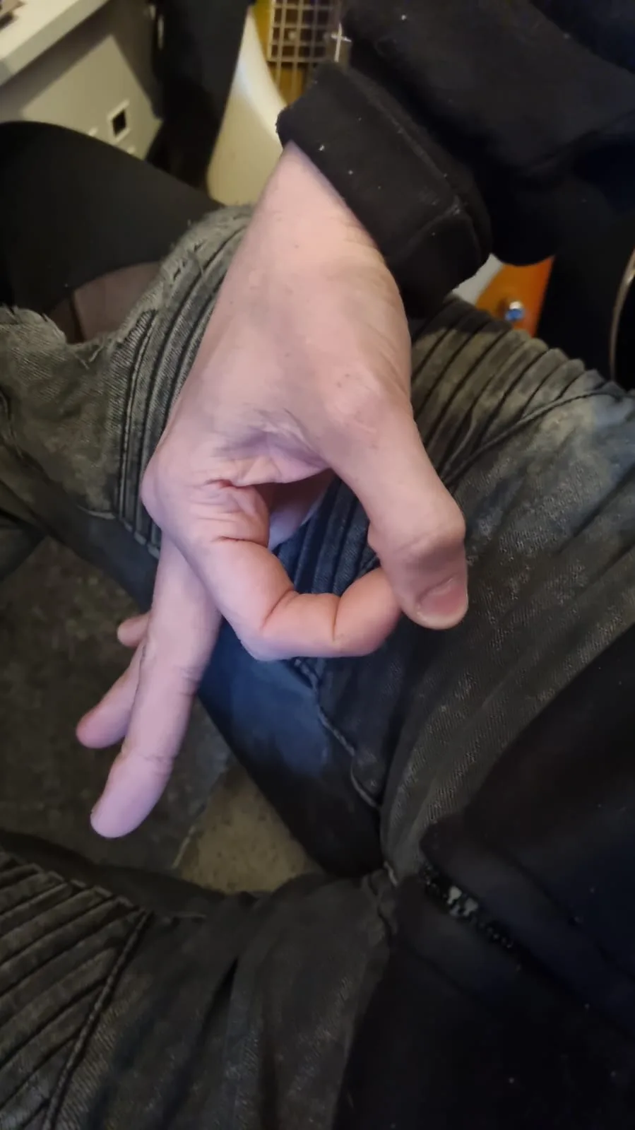 A close-up photo shows a person's hand making a gesture with the thumb and index finger forming a circle while the other…