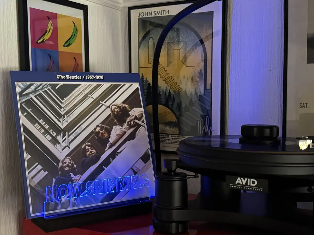 A framed, illuminated Beatles album cover from 1967-1970, featuring the band looking down from a building, has the glowing…