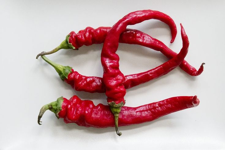 Four bright red, wrinkled chili peppers with green stems are arranged on a plain white surface. The text overlay reads 'I'm…