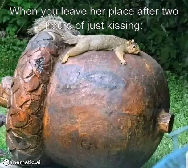 A real squirrel is lying relaxed on top of a large wooden sculpture of a person's head, which is carved with a visible neck…
