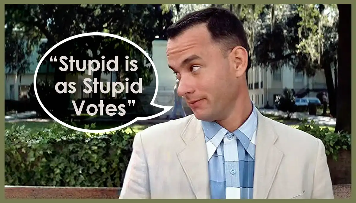 A man in a light-colored suit and blue checkered shirt looks sideways with a skeptical expression, as a white speech bubble…