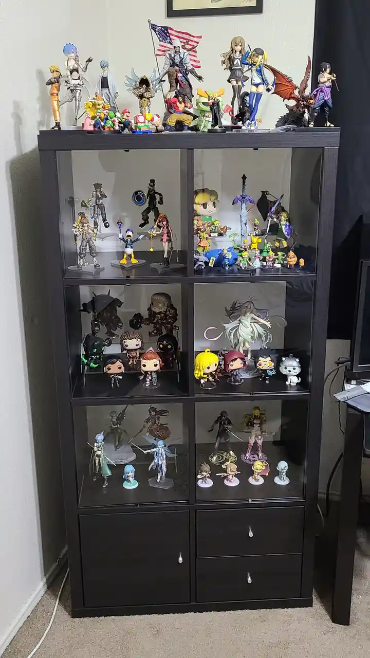 A tall black display cabinet filled with numerous anime and video game figurines across multiple glass-fronted shelves, with…