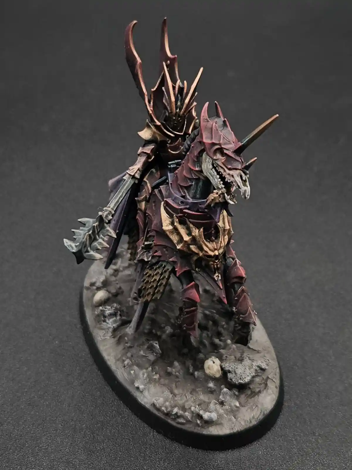 A highly detailed, painted miniature of a dark fantasy warrior riding a skeletal, armored dragon-like creature. The rider…