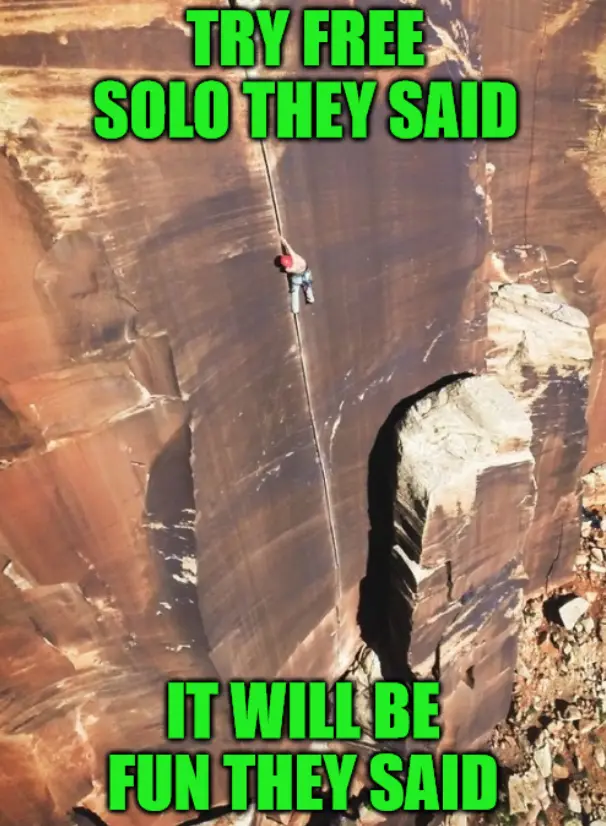 A climber is shown scaling a sheer, reddish-brown rock face with a rope, positioned high above the ground. The image has…