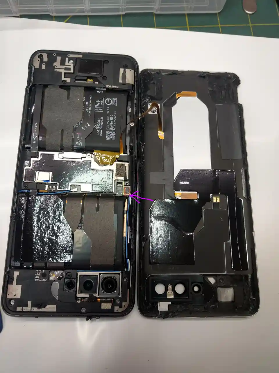 The image shows the internal components of a disassembled smartphone, with the front panel separated from the back. A purple…