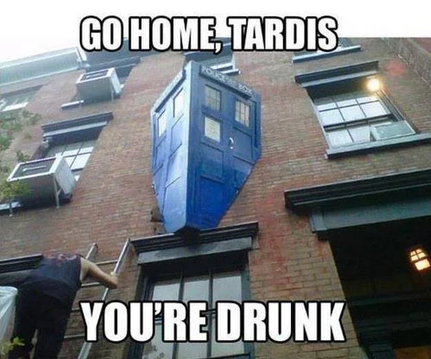 A blue police box, known as the TARDIS from Doctor Who, is precariously balanced on the ledge of a brick building, appearing…
