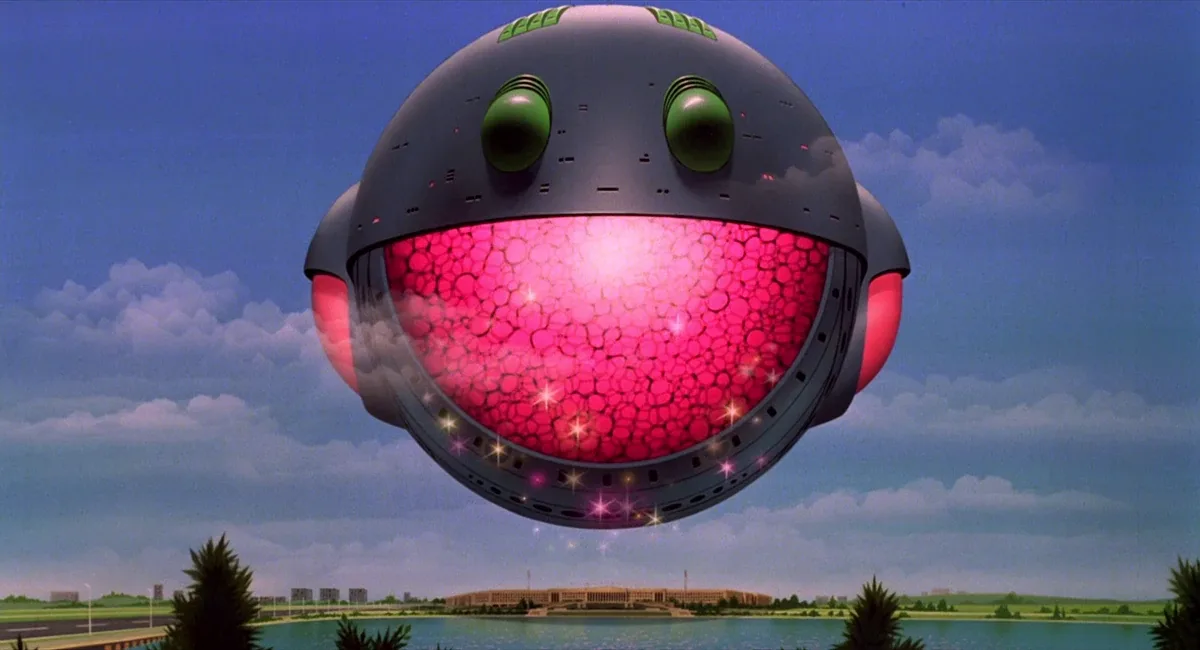 A giant, spherical, gray robot with large green eyes and a glowing pink, bubble-textured mouth hovers over a cityscape with…