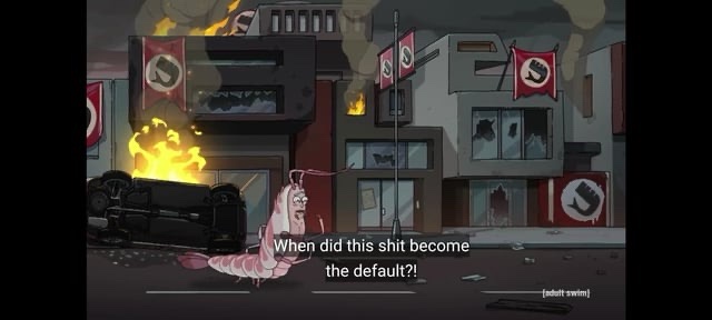 A pink, anthropomorphic shrimp character stands in a war-torn, burning city street with overturned cars and buildings…