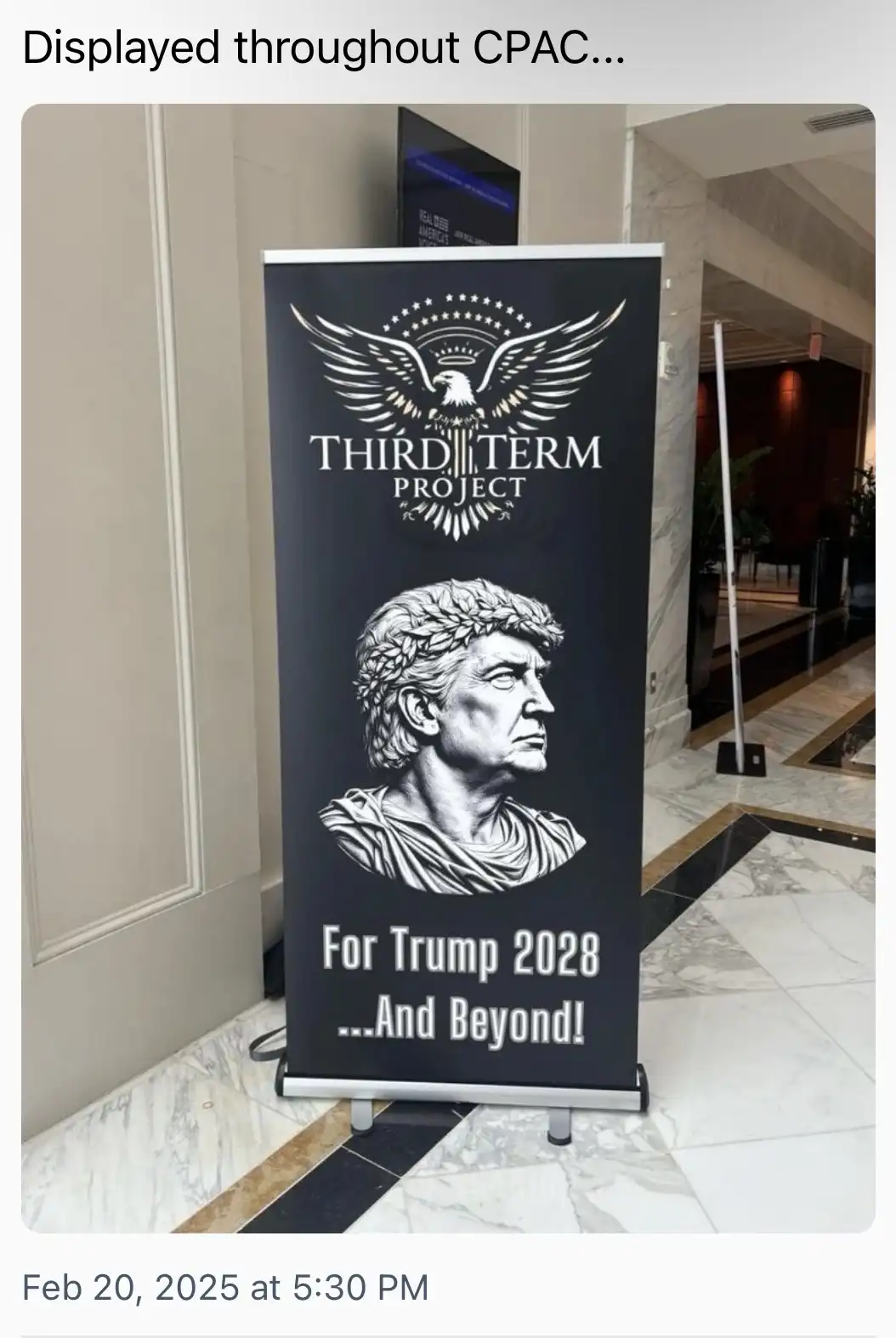 A black banner standee at a convention displays a logo with an eagle and stars above the text 'THIRD TERM PROJECT'. Below, a…