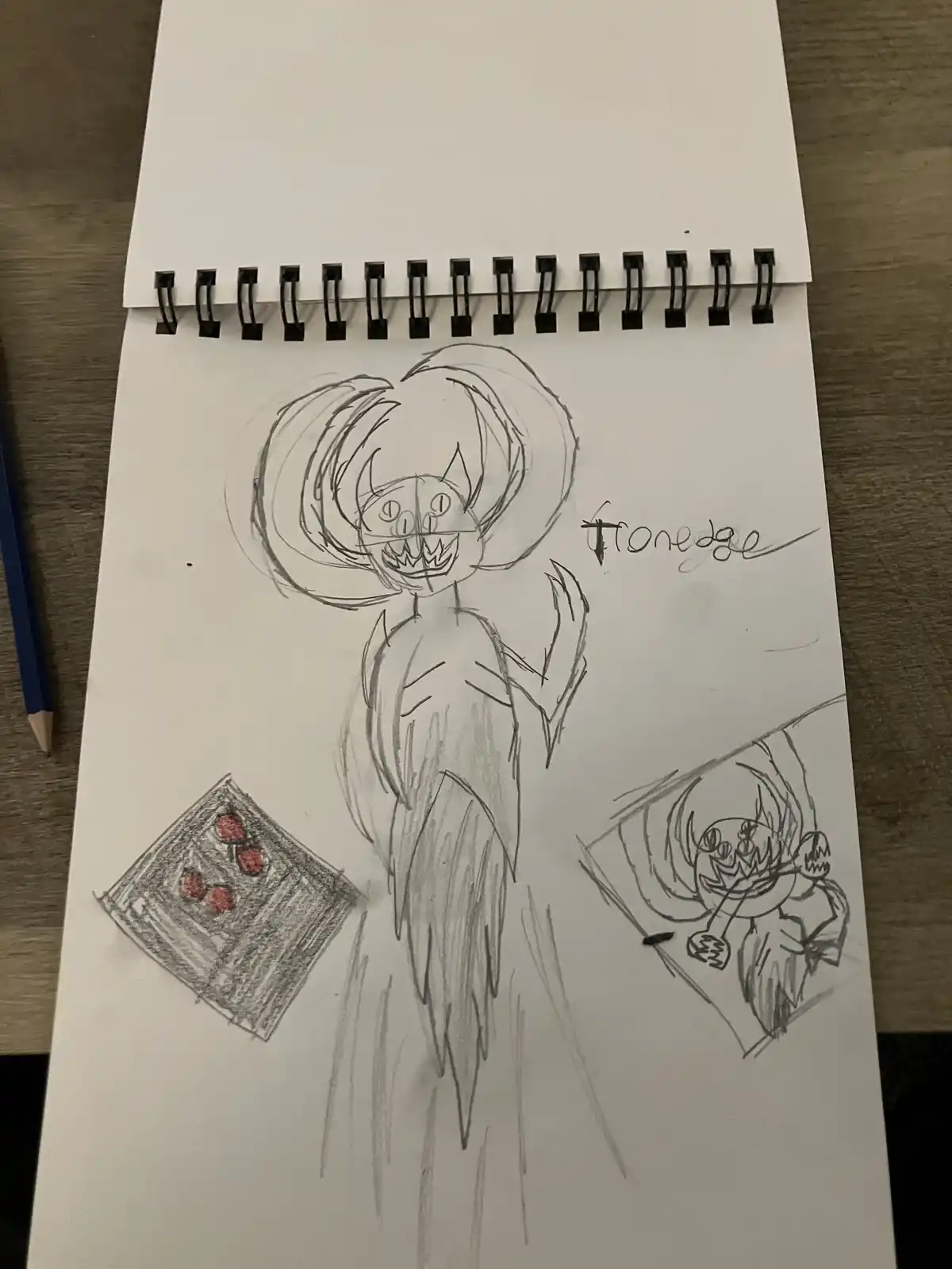 A hand-drawn sketch on a spiral-bound notebook page shows a cartoonish, menacing character with a wide grin, sharp teeth…