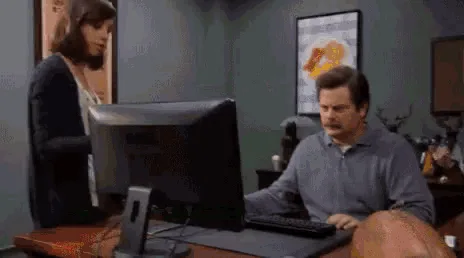 A man in a blue polo shirt is shown in a sequence of images: first sitting at a desk looking annoyed, then carrying a large…