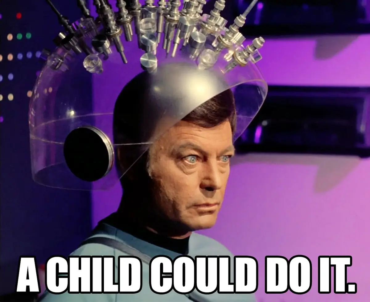 A man with a serious expression wears a transparent dome helmet with numerous metal probes and tubes attached to his head…