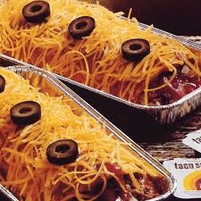Two foil trays of chili topped with shredded cheese and black olives, with the text 'faco es' overlaid in the bottom right…