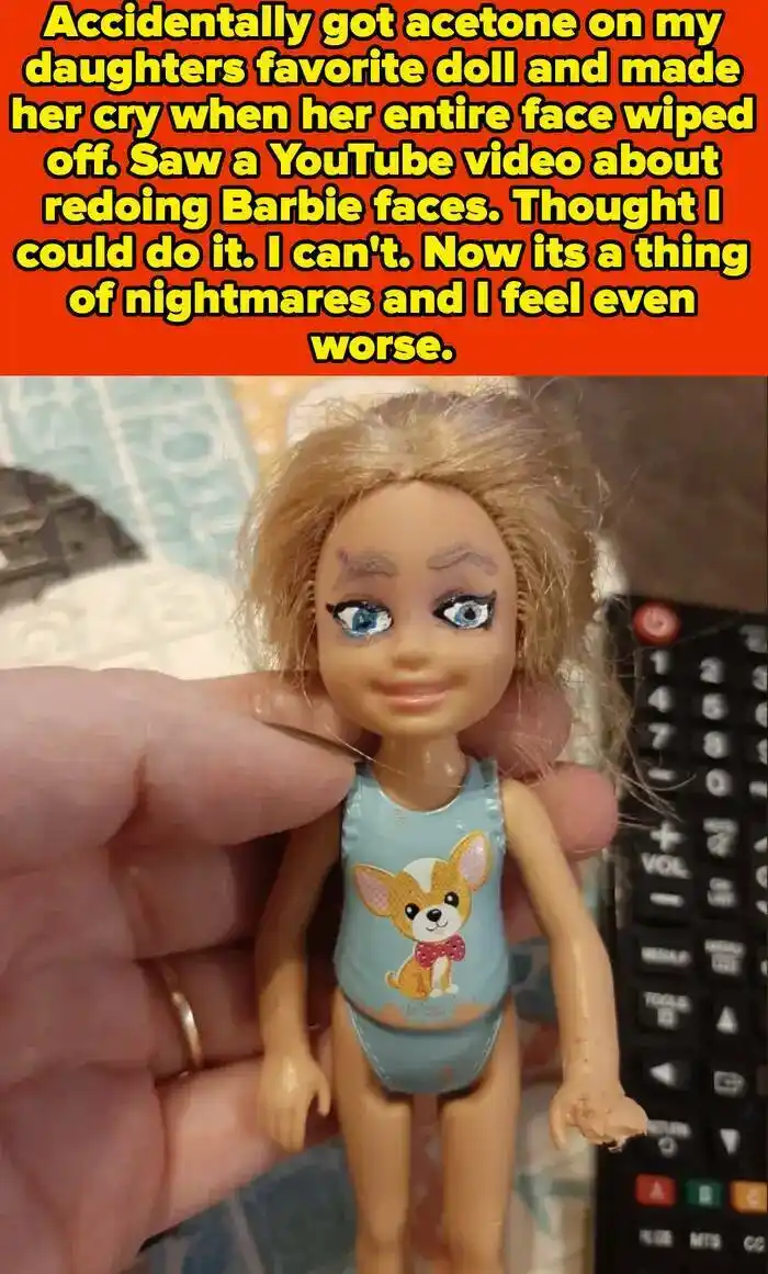 A close-up photo shows a hand holding a doll with a partially peeled-off face, revealing the plastic underneath. The doll…