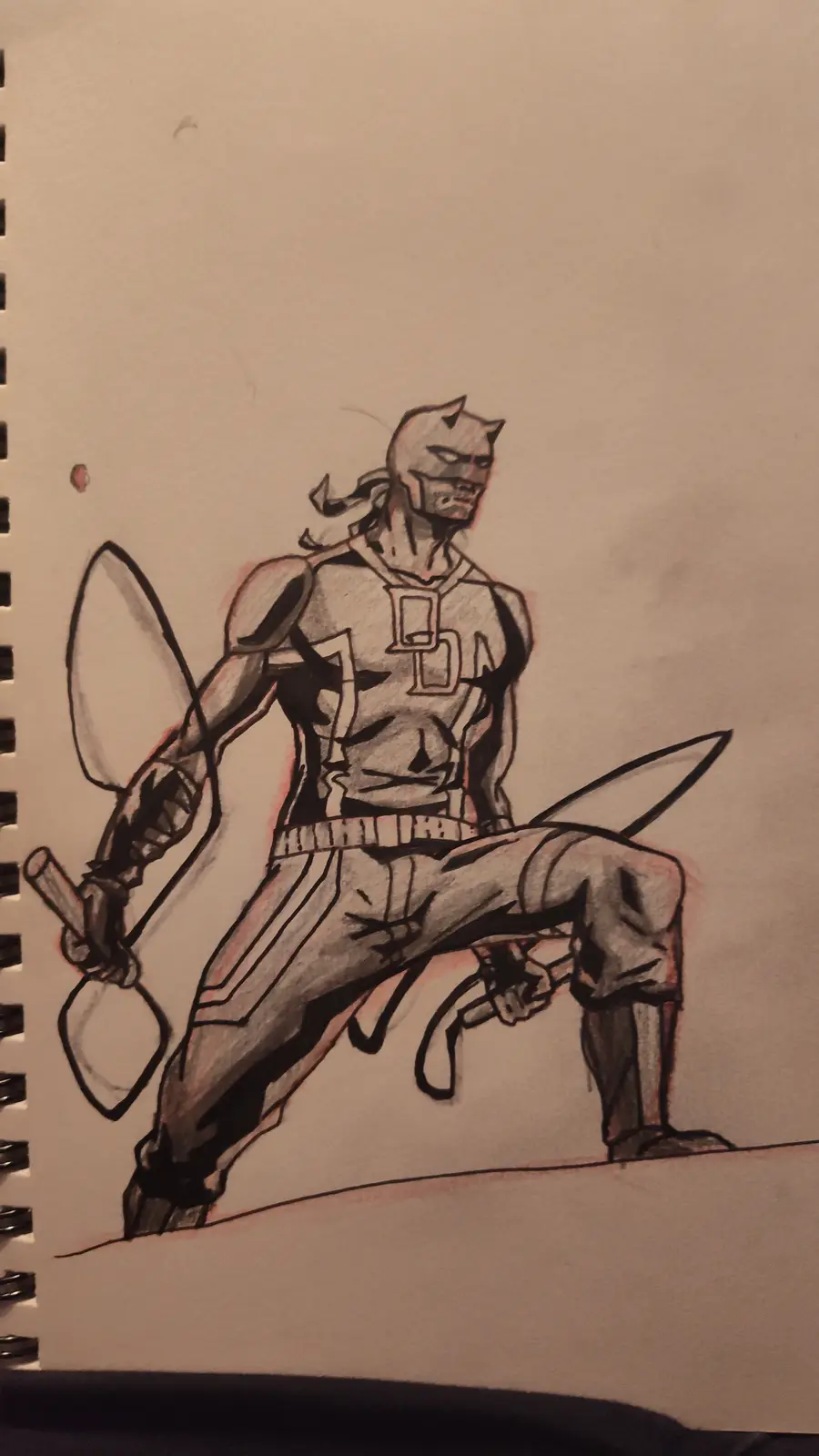 A hand-drawn sketch on spiral-bound notebook paper depicts a muscular, masked figure with cat-like ears and a stern…